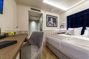 a bedroom with a bed and a desk with a chair at Grand Hotel Slavia in Ba&scaron;ka Voda