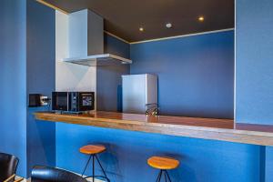 a kitchen with blue walls and a counter with stools at La-gum - Vacation STAY 42137v in Inatori