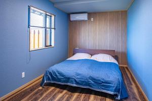 a bedroom with a bed with blue walls and a window at La-gum - Vacation STAY 42137v in Inatori
