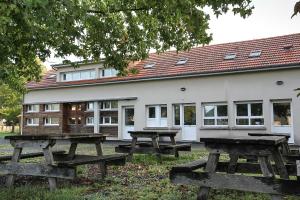 un gruppo di tavoli da picnic di fronte a un edificio di Auberge de Jeunesse HI Genêts a Genêts