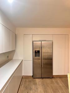 a stainless steel refrigerator in a kitchen with white cabinets at Spacious Central London flat - 2BHK in London