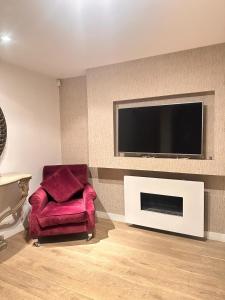 a living room with a red chair and a flat screen tv at Spacious Central London flat - 2BHK in London