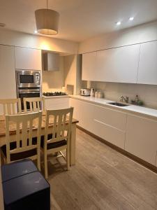 a kitchen with white cabinets and a table and chairs at Spacious Central London flat - 2BHK in London