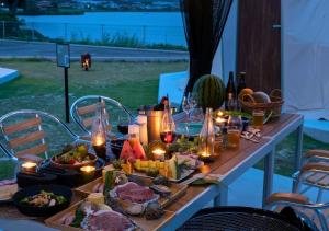 出雲市にあるGlamping Base IZUMO "Lakeside Hot Spring Hotel Kun - Vacation STAY 42019vの食べ物とキャンドルとワインのボトルを用意したテーブル