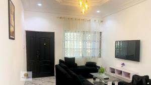 sala de estar con sofá negro y TV en Beautiful 2-Bed Apartment in Accra en Accra