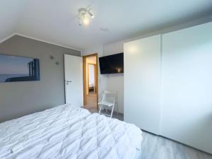 a bedroom with a white bed and a chair at Haus Glücksfang in Hooksiel in Wangerland +13 photos