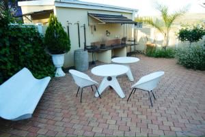 a patio with two white tables and chairs on a brick ground at Longtom Farm Guesthouse in Lydenburg