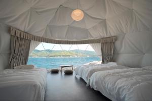 eine Reihe von Betten in einem Raum mit dem Wasser in der Unterkunft TADAYOI - Sea Glamping - Vacation STAY 42100v in Hishi