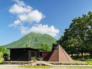 una pequeña casa con una montaña en el fondo en Sense of wonder Yufudake Sanroku Glamping Resort - Vacation STAY 41962v, en Yufu