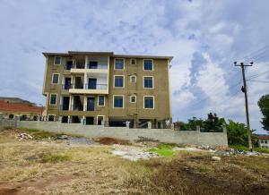 a tall yellow building with blue windows in a field at ATA Luxe Apartments in Kira