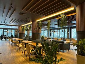 Un restaurante con mesas, sillas y plantas. en Aparthotel Zlatni Javor - Apartman 511, en Jahorina