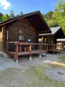 Nasu Takahara Auto Campsite - Vacation STAY 42064v في ناسوشيوبارا: كابينة خشب أمامها مقاعد