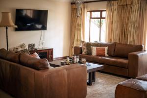 a living room with two couches and a tv at White River Country Estate - Self Catering - AMH Home in White River