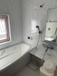 a bathroom with a tub and a toilet and a sink at Camp inn Kiyosato GRANDEUR - Vacation STAY 42082v in Hokuto