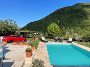a swimming pool with a red car parked in front of a mountain at La Stala in Pieve di Teco