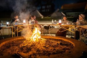 grupa ludzi siedzących przy stolikach wokół ognia w obiekcie Tanesashi Campsite - Camp - Vacation STAY 42214v w mieście Hachinohe