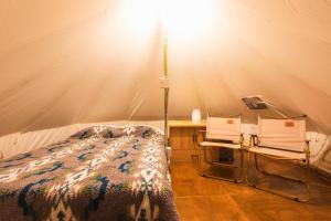 ein Bett und zwei Stühle in einem Zelt in der Unterkunft SPRINGS VILLAGE Ashigara-Tanzawa Hot Spring Resort & Glamping - Vacation STAY 42311v in Oyama