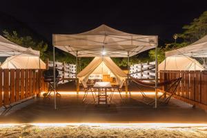 ein Zelt mit Tischen und Stühlen unter Sonnenschirmen in der Nacht in der Unterkunft SPRINGS VILLAGE Ashigara-Tanzawa Hot Spring Resort & Glamping - Vacation STAY 42311v in Oyama