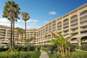 a large building with palm trees in front of it at Tim - 2min de la mer - Piscine - Terrasse - VCA in Cannes