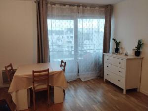 een eetkamer met een tafel en een raam bij Superbe appartement avec 3 chambres à 700 mètres du stade de France in La Plaine-Saint-Denis