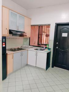 a kitchen with white cabinets and a black door at Maricel homestay in Kota Kinabalu