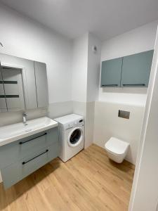 a white bathroom with a washing machine and a toilet at YOURAPART Letnicka Sea in Gdańsk