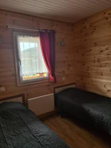Dormitorio con cama y ventana en una cabaña de madera en Chalet au coeur du parc du Morvan - Moux-en-Morvan, en Moux-en-Morvan