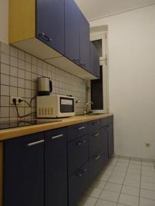 een keuken met blauwe kasten en een magnetron bij Apartment Essen-City in Essen