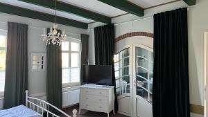 a bedroom with a bed and a tv and a window at Huus Achterdiek - Whg Anker in Dornumersiel
