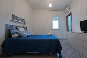 a bedroom with a blue bed and a television at Villa Al Mare Guest House in Tre Fontane