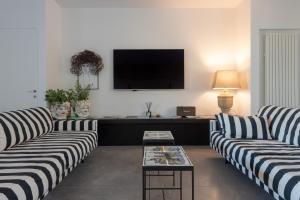 sala de estar con 2 sofás y TV de pantalla plana en Villa Vogue - IsulaTravel, en Avola