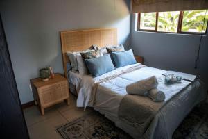 a bedroom with a bed with blue pillows and a window at White River Country Estate - Self Catering - AMH Home in White River +42 photos