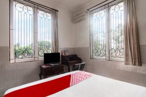 una camera con letto, scrivania e finestre di OYO 93499 Pondok Sentosa Near UPH a Giacarta