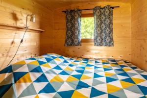 ein Schlafzimmer mit einem farbenfrohen Bett in einem Holzzimmer in der Unterkunft Domaine de la Cambre in Duffort