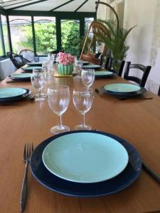 een houten tafel met borden en wijnglazen erop bij Grande maison #6 chambres #Proche Amboise/Tours in Mosnes