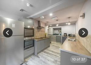eine große Küche mit Küchengeräten aus Edelstahl und grauen Schränken in der Unterkunft Immaculate 6-Bed Ivy house in Doncaster