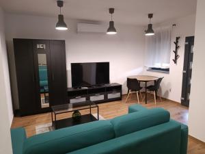 uma sala de estar com um sofá azul e uma mesa em Apartmani Jana em Osijek