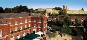 an old red brick building with a castle in the background at Charlotte House in Lincoln