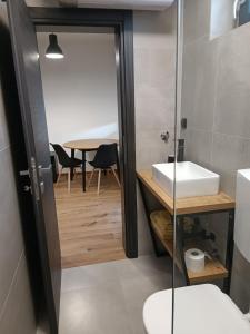 uma casa de banho com um lavatório, um WC e uma mesa em Apartmani Jana em Osijek