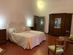 een slaapkamer met een wit bed en een stoel bij Fienile in Castelnuovo Berardenga