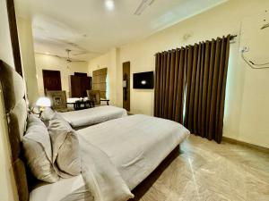 ein Hotelzimmer mit 2 Betten und einem TV in der Unterkunft Shelton Hotel Lahore in Lahore