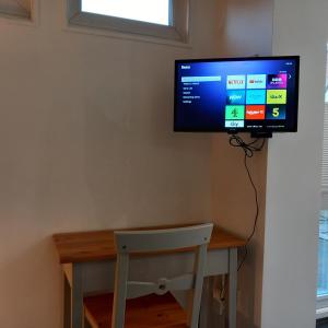 a flat screen tv on a wall above a desk at Thistles -Private Entrance Studio 