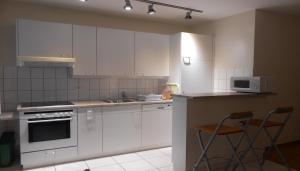 a kitchen with white cabinets and a counter with two chairs at Athénée 40 Residence by Homenhancement in Geneva