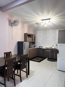 una cucina con tavolo, sedie e frigorifero di Aina Guest House a Kota Bharu