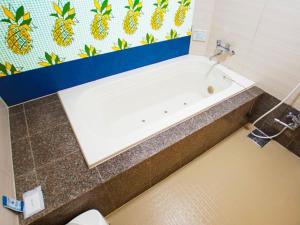 Una bañera en un baño con una pared de piña. en Hotel Firstwood 大栄店, en Narita