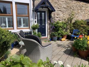 a patio with wicker chairs in front of a house at Sunnieside Cottage in Seahouses