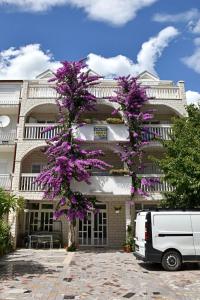 a van parked in front of a building with purple flowers at Apartments Cipetic in Kaštela