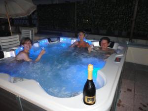 three people in a hot tub with a bottle of champagne at Hotel Mariani in Lido di Camaiore