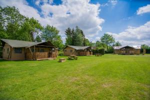 un groupe de cottages dans un champ avec de l'herbe dans l'établissement Glamping Drouwenerzand - Danny's Lodge, à Drouwen