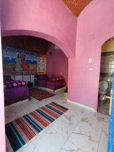 uma sala de estar com paredes cor-de-rosa e mobiliário roxo em Kamel House em Aswan